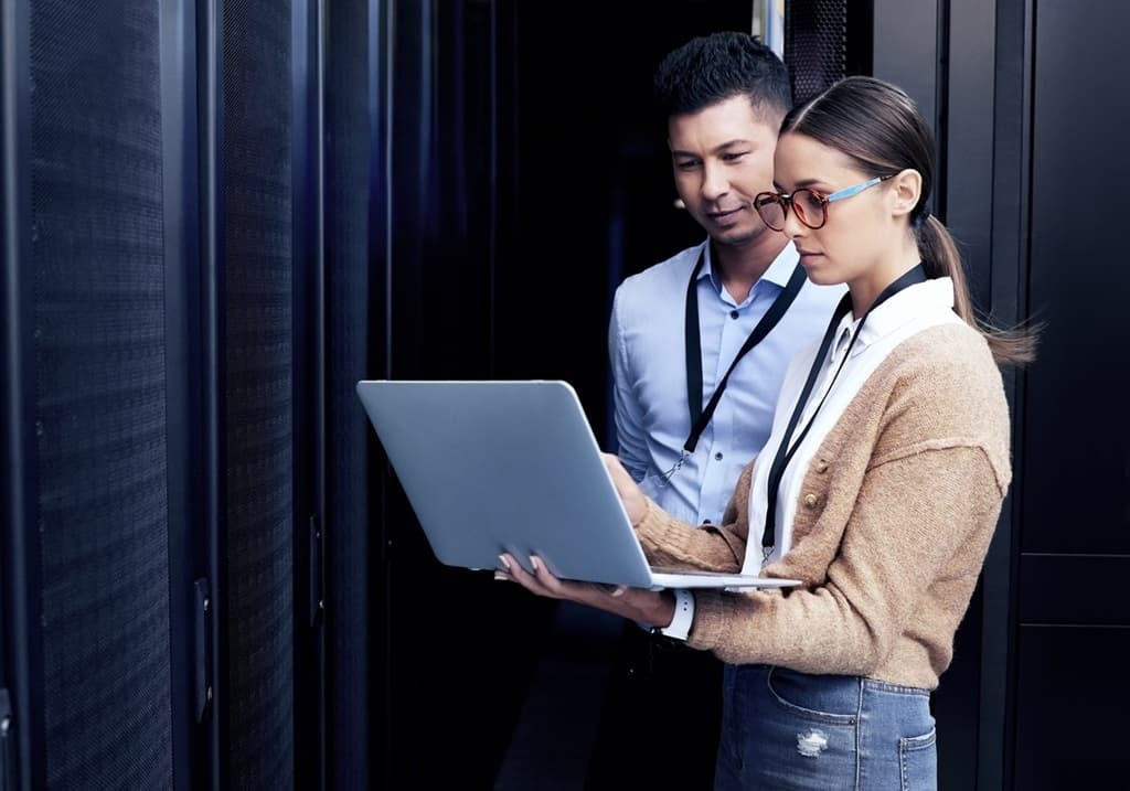 Zwei IT-Mitarbeiter mit Laptop im Serverraum