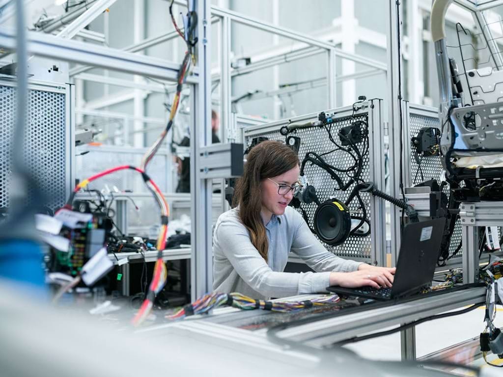 Frau bei der Arbeit am Laptop im modernen Produktionsumfeld