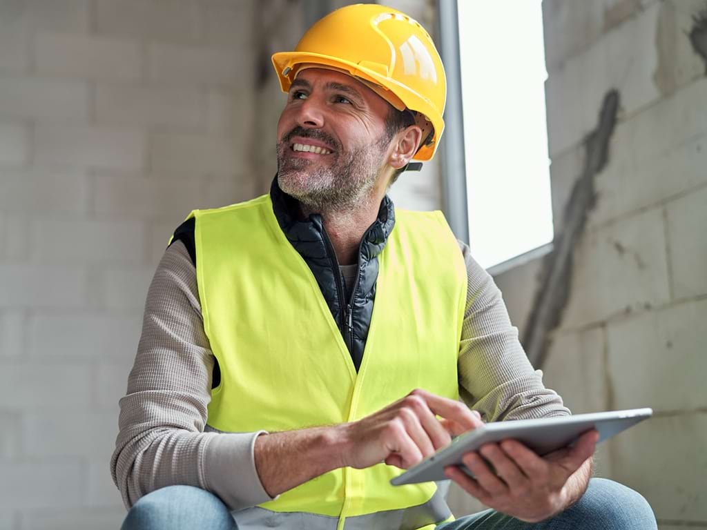 Mann bei der Arbeit auf der Baustelle mit einem Tablet; © iStock 1367813740 gpointstudio