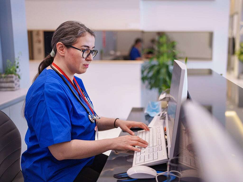 Pflegefachkraft am Computer in einer Gesundheitseinrichtung; © iStock 2208103894